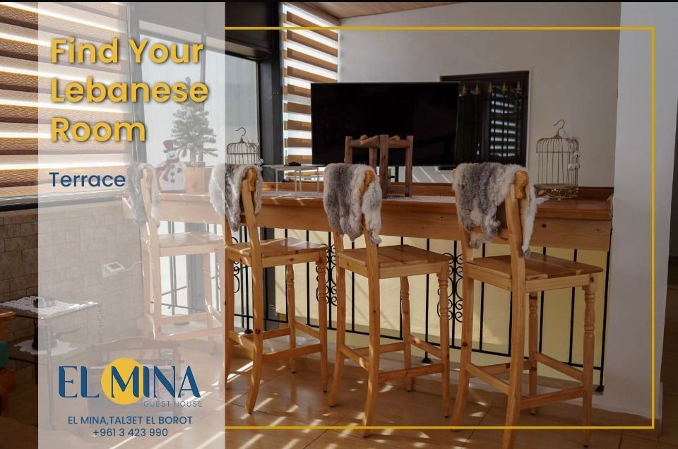 Terrace seating area with wooden bar stools and decorative items at El Mina Guest House.